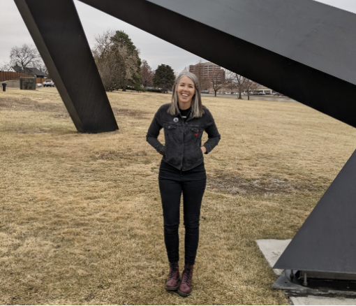 Alison from the PAA team standing outside in front of a black sculpture in the park.
